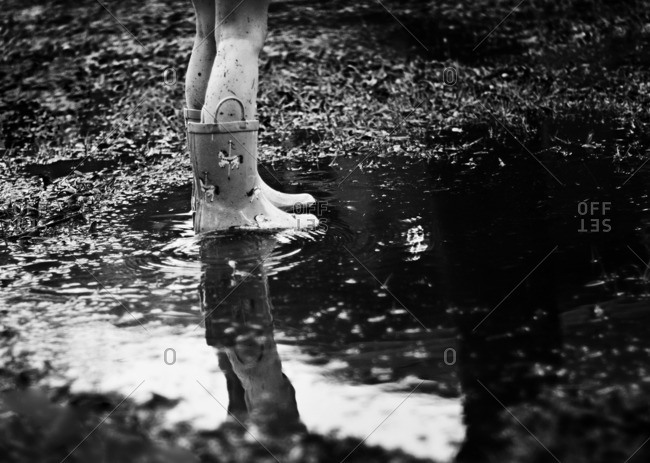 Girl in rain boots standing in a puddle