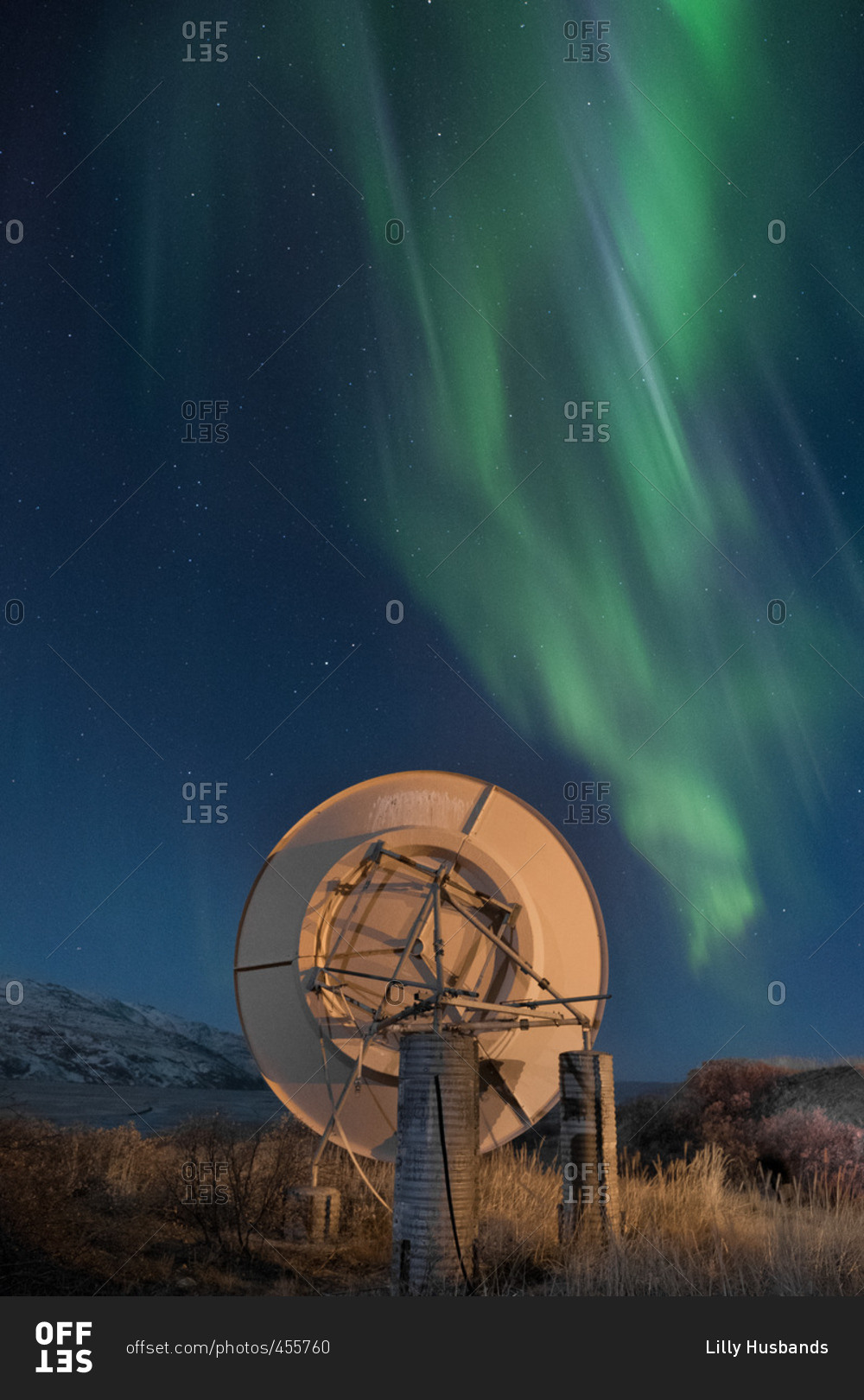 Aurora borealis over mountains and satellite dish in Greenland