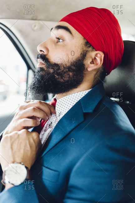 Indian businessman binding tie in a taxi
