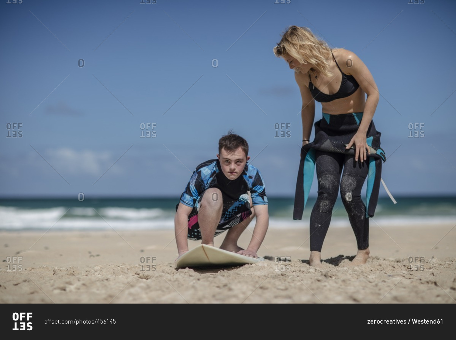 Teenage boy with down syndrome having surf lessons on beach