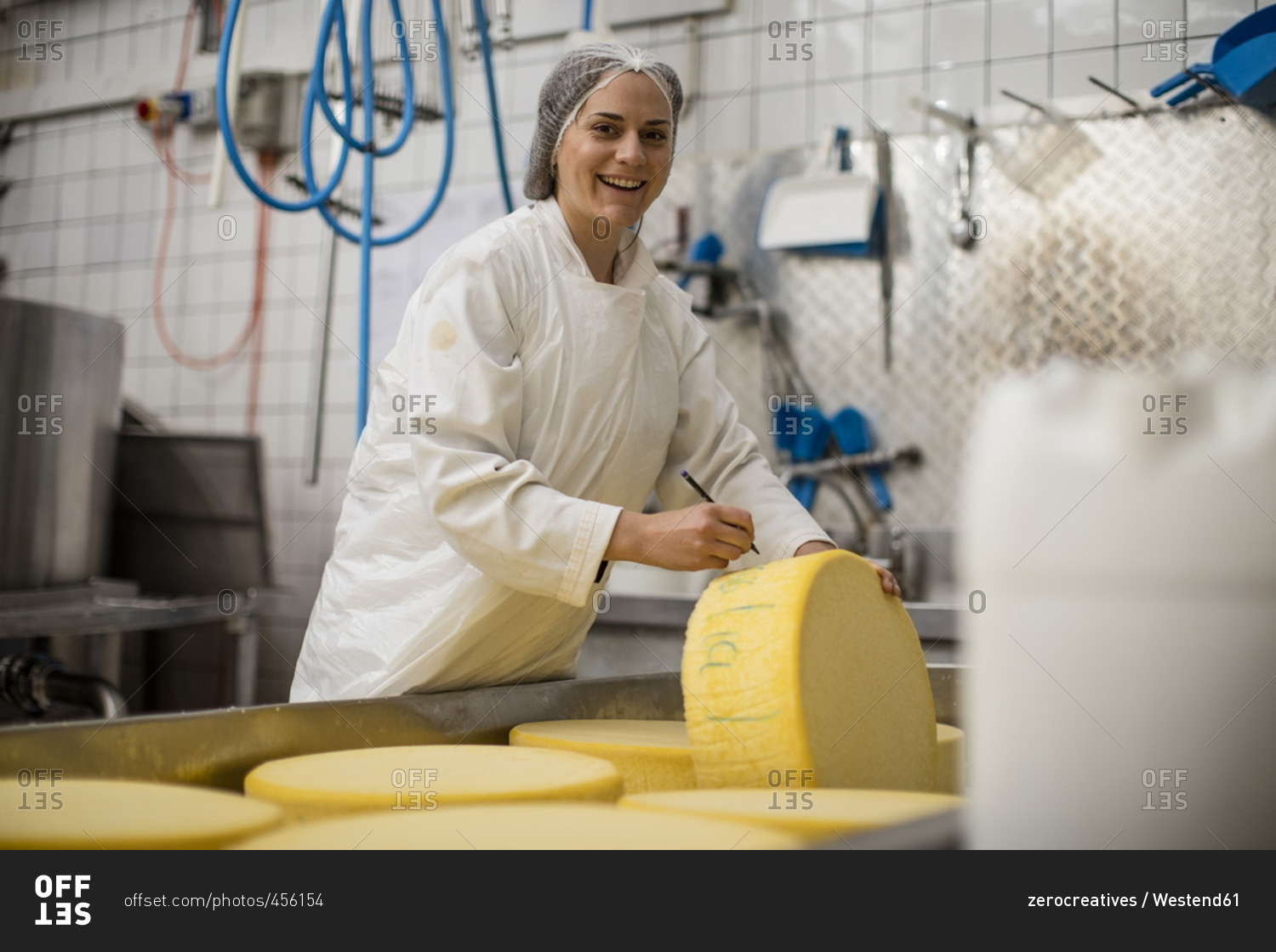 Cheese factory worker labelling cheese wheel