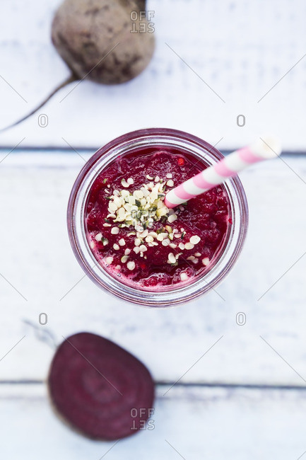 Glass of beetroot smoothie with hemp seed and whole and sliced beetroot
