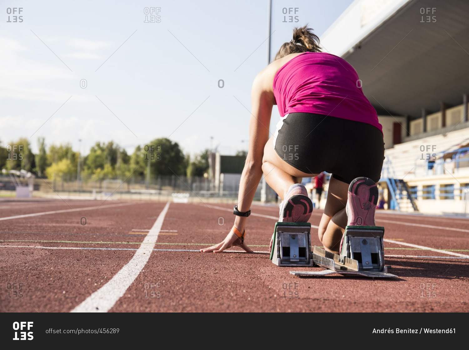Female runner on tartan track in starting position