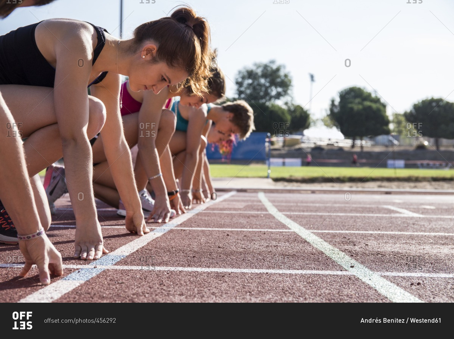 Female runners on tartan track in starting position