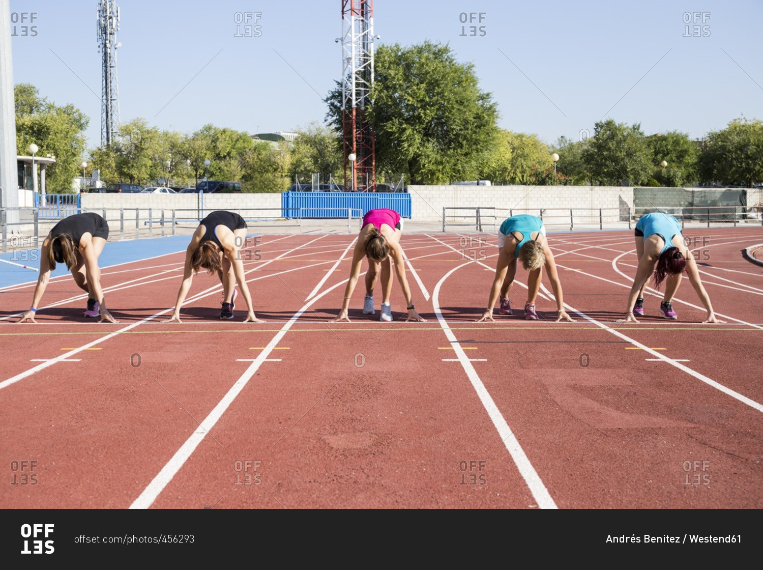 Female runners on tartan track in starting position