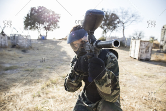 Paintball player aiming with paintball gun during a paintball game