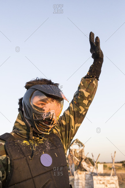 Paintball player with arm raised after being eliminated in a paintball game