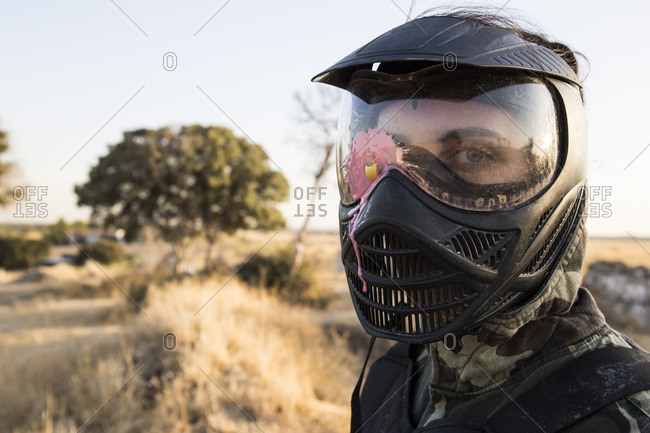 Female paintball player with paintball mask stained with paint
