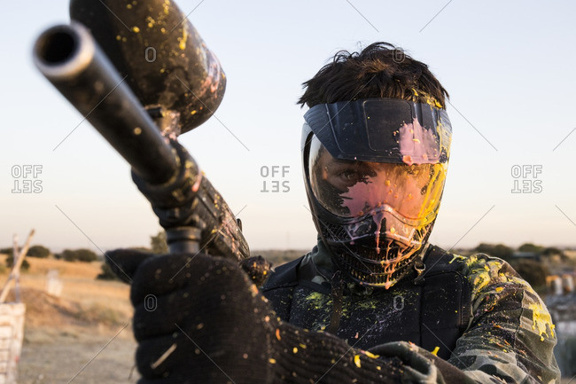Paintball player with paintball mask and paintball gun stained with paint