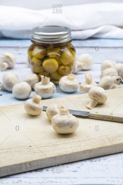 Fresh white champignons and glass of pickled champignons