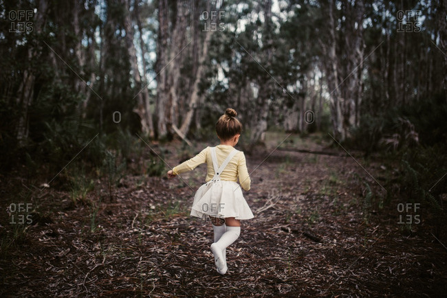 Little girl running in the woods from behind