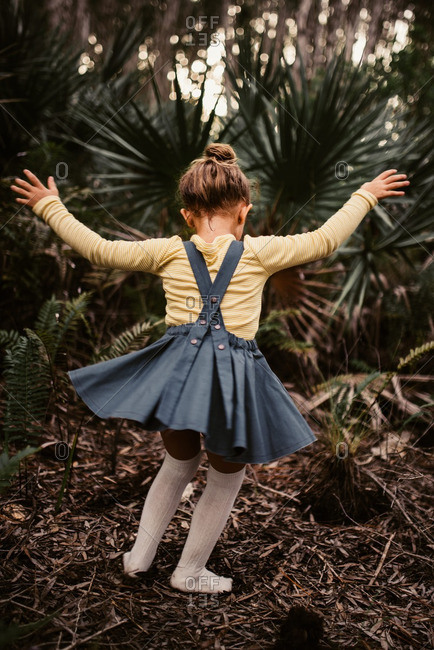 Rear view of little girl dancing in the woods