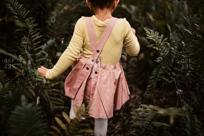 Little girl walking through plants in the woods