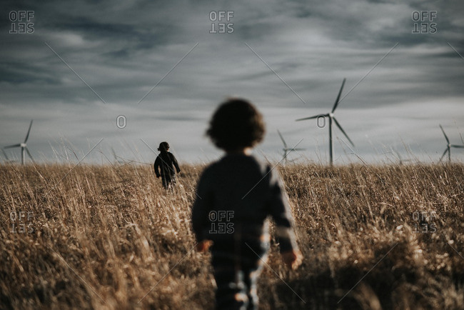 Boys walking through a field with wind turbines