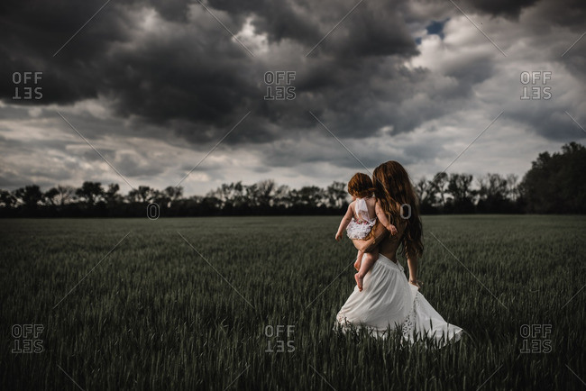 Mother holding daughter while walking in a field
