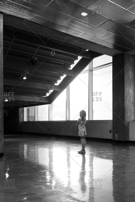 Little girl standing under staircase by windows