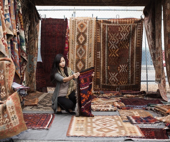 Chinese woman shopping for rugs in flea market