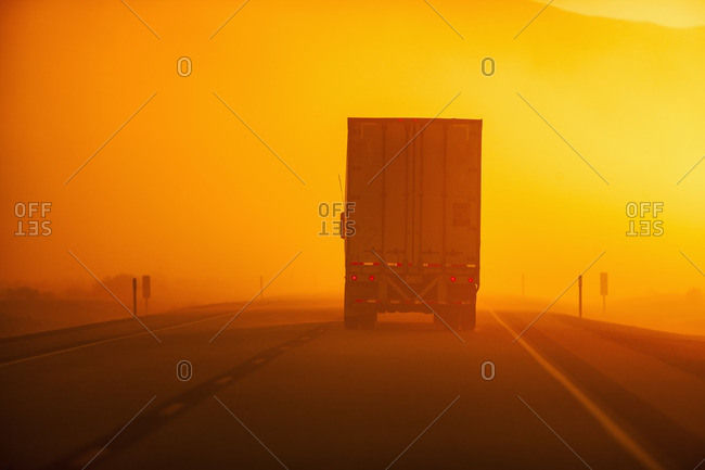 Truck driving down road in dust storm