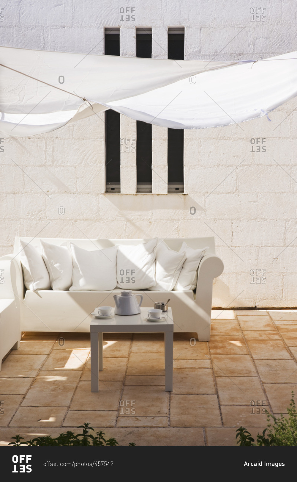 Sofa under a white shade sail over the terrace of an Italian house