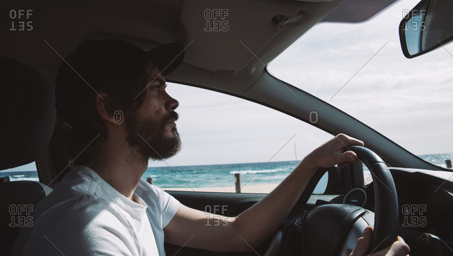 Young man driving car by sea