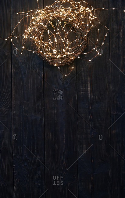 Christmas wreath and fairy lights on a wooden wall