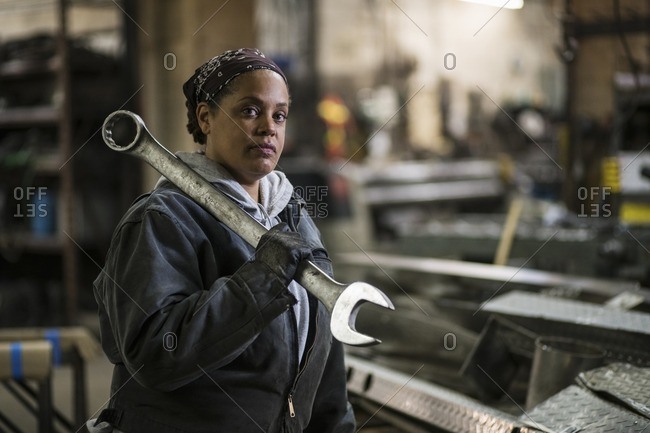 African American worker holding wrench in factory
