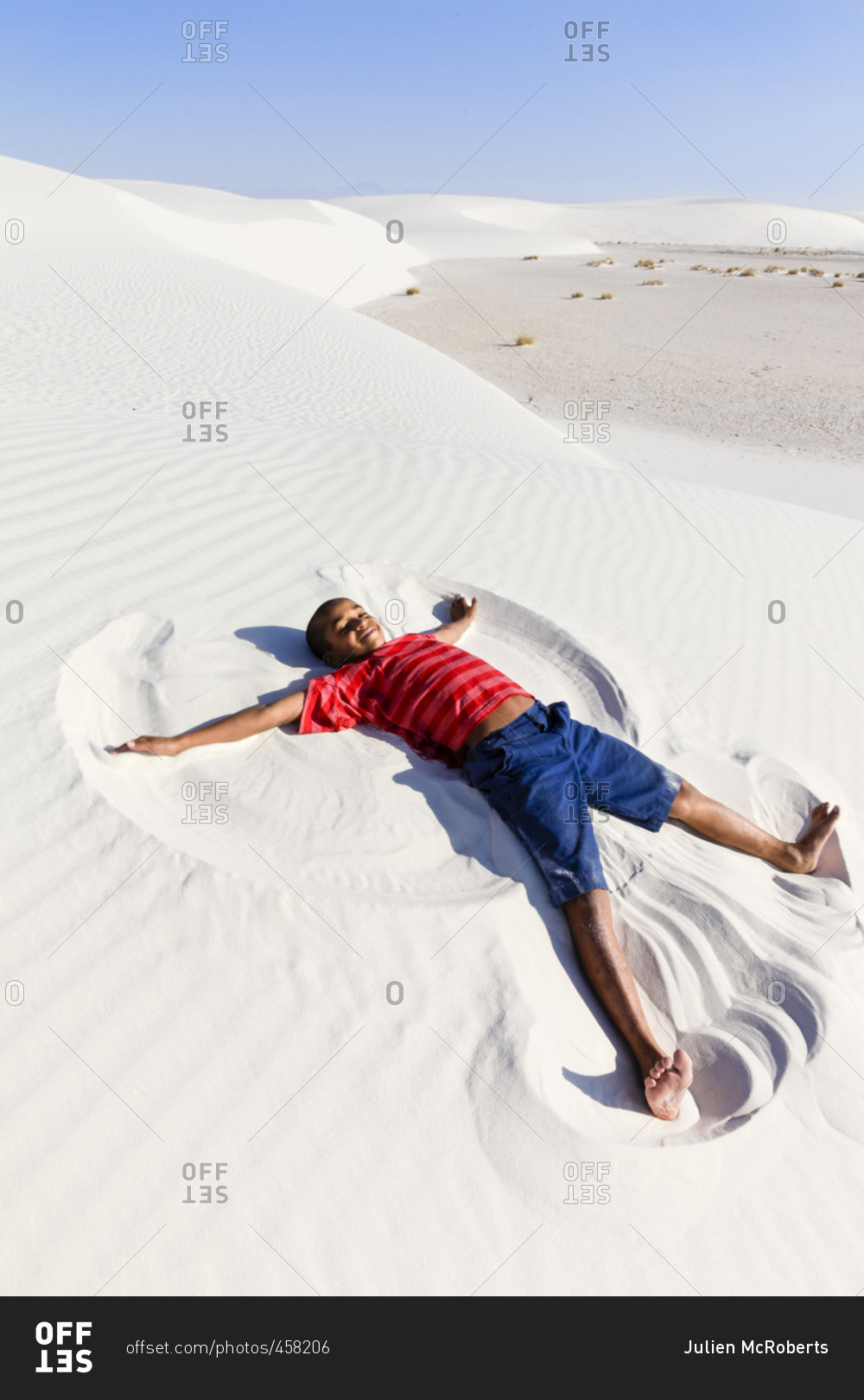A young boy creating a \'sand angel\' in the desert of the White Sands National Monument