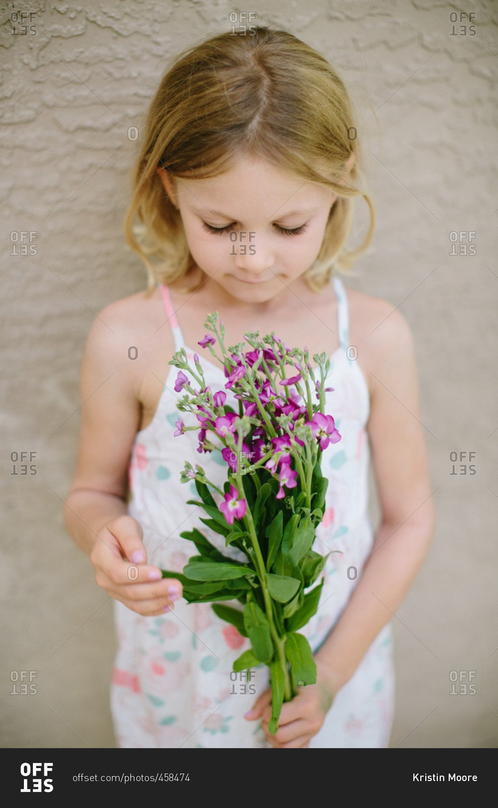 Little girl holding bunch of purple flowers