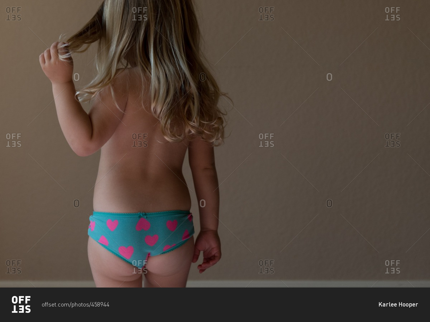 Little girl wearing blue panties with pink hearts stock photo - OFFSET