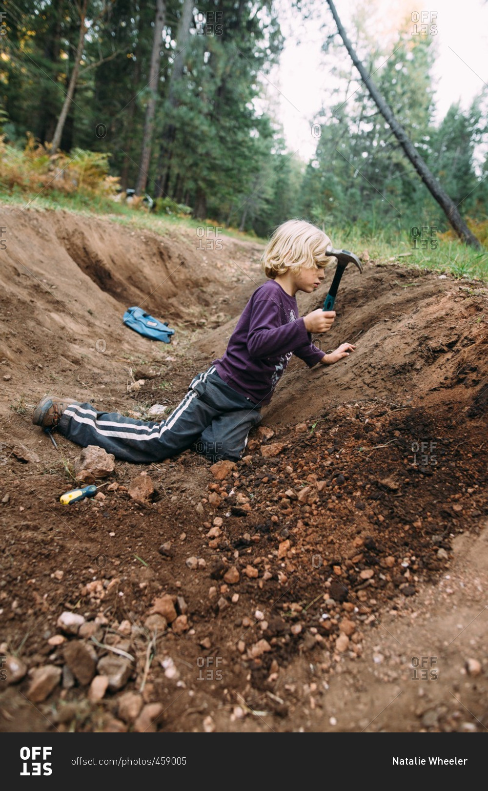 Boy digging in hole with hammer