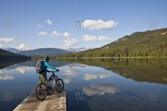 A male mountain biker enjoys a peaceful moment in the morning before an all day ride in Spruce Lake Protected Area, Southern Chilcotins, British Columbia, Canada