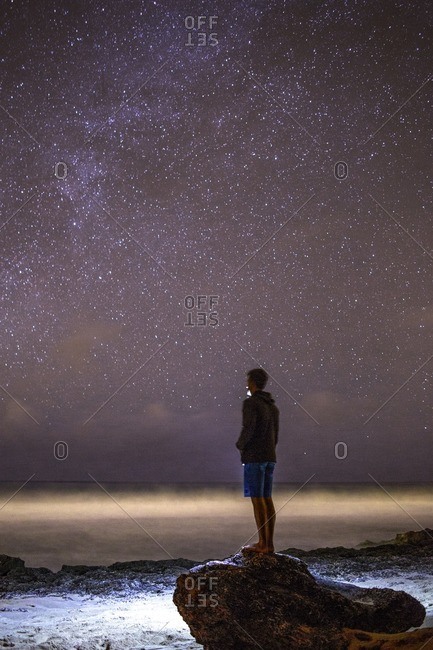 A man watches the waves beneath the Milky Way.