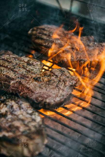 Steaks cooking in flames of grill