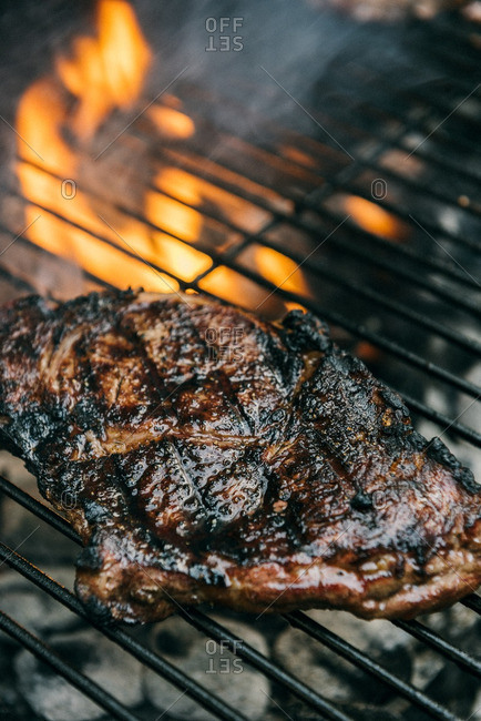 Steak cooking over flames on grill