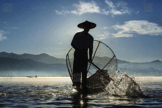 Fisherman rowing canoe on water
