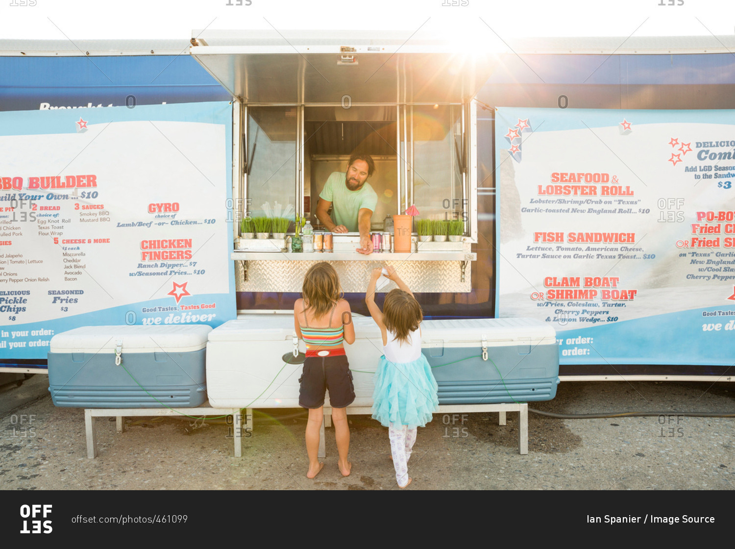 Man in fast food trailer serving two young girls beside trailer
