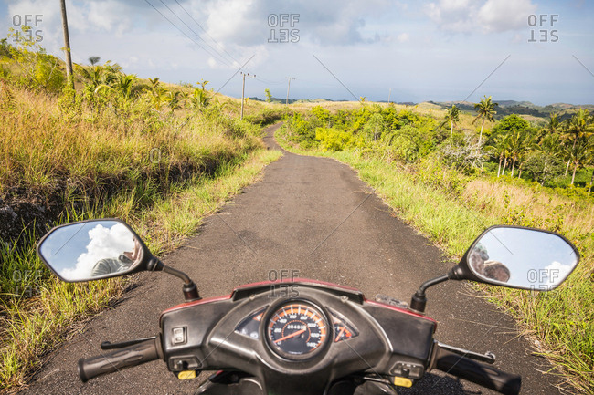 Mirror image of motorcyclist in motorcycle wing mirrors on rural road, Tanglad, Nusa Penida, Indonesia