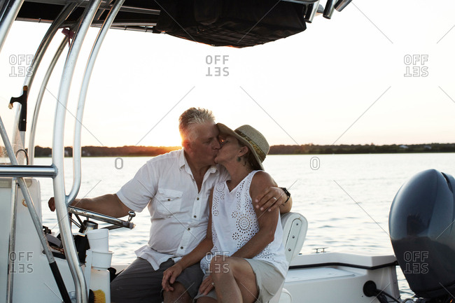 Senior couple, sitting on boat, kissing