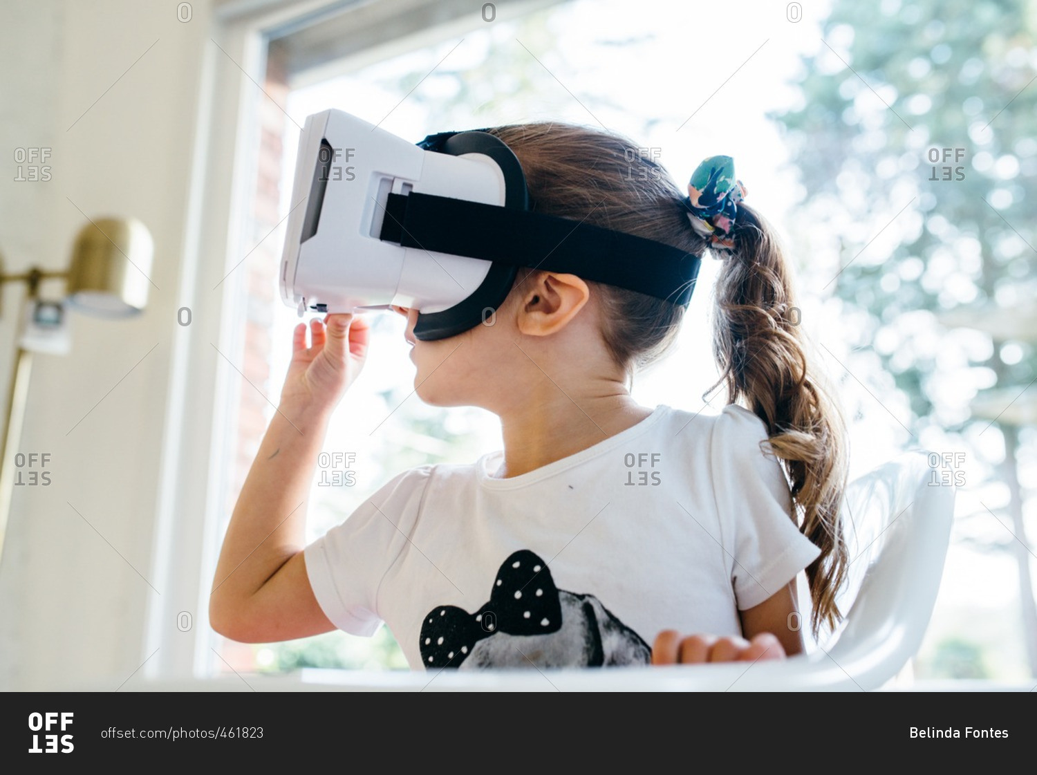 Little girl in front of a window wearing a virtual reality headset