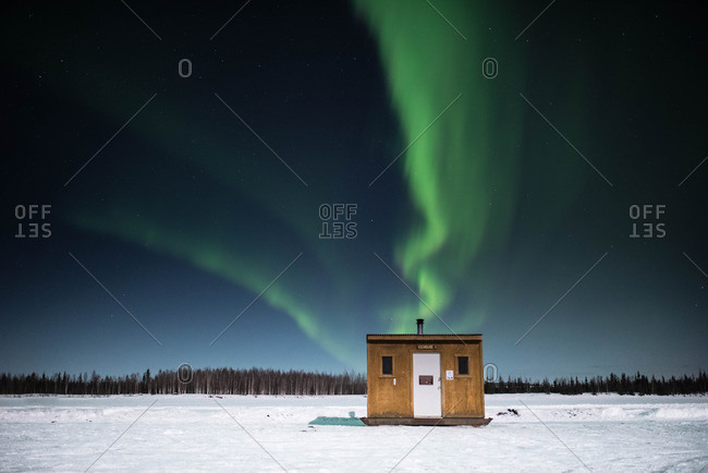 Ice fishing hut under Northern Lights