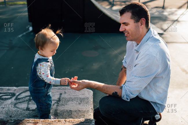 Toddler girl handing something to her father