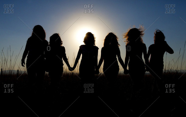 Silhouettes of girls walking in tall grass