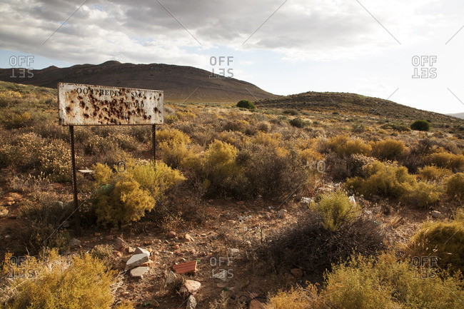 Wasteland landscape with broken sign and distant mountains