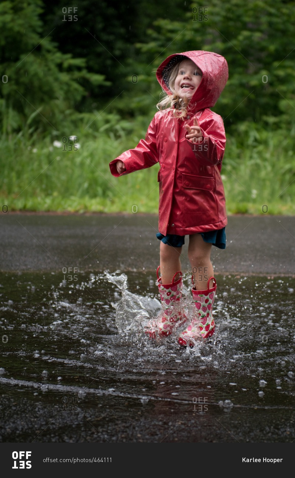 Happy young girl jumping in puddle stock photo - OFFSET