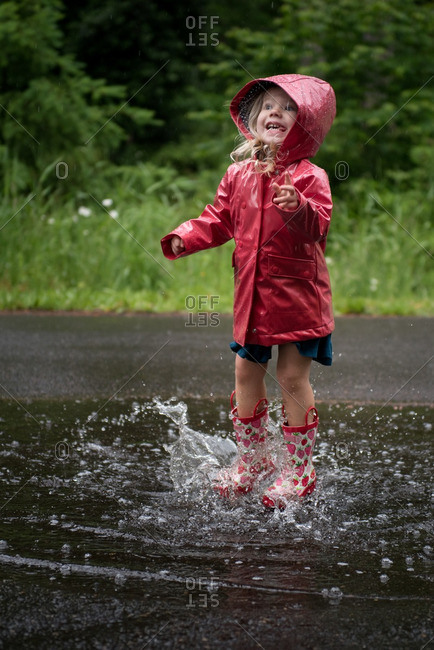 Happy Young Girl Jumping In Puddle Stock Photo - Offset