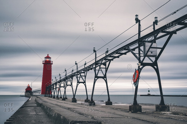 Electricity Pylons And Lighthouse On Pier Amidst Sea Against - 