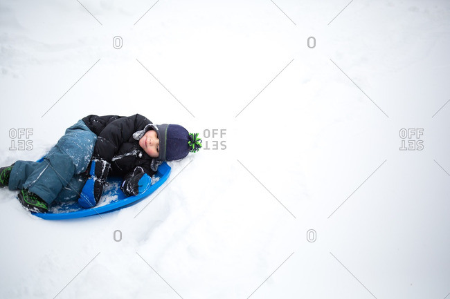 Boy lying in saucer-shaped sled