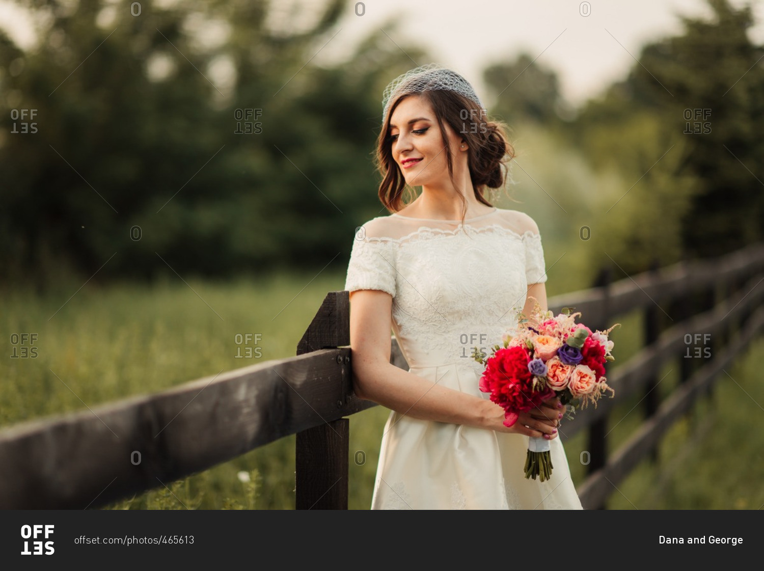 Bride with bouquet by rural fence