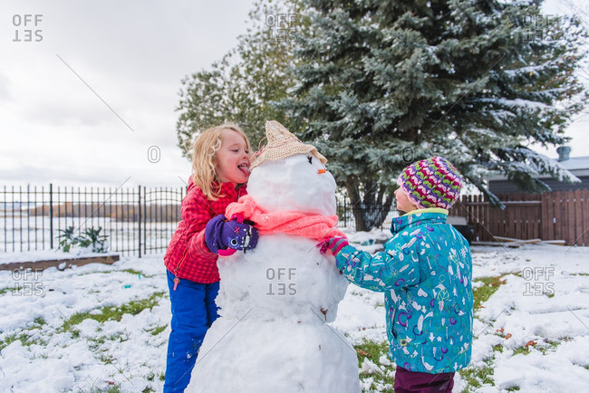 Girl licking a snowman in yard