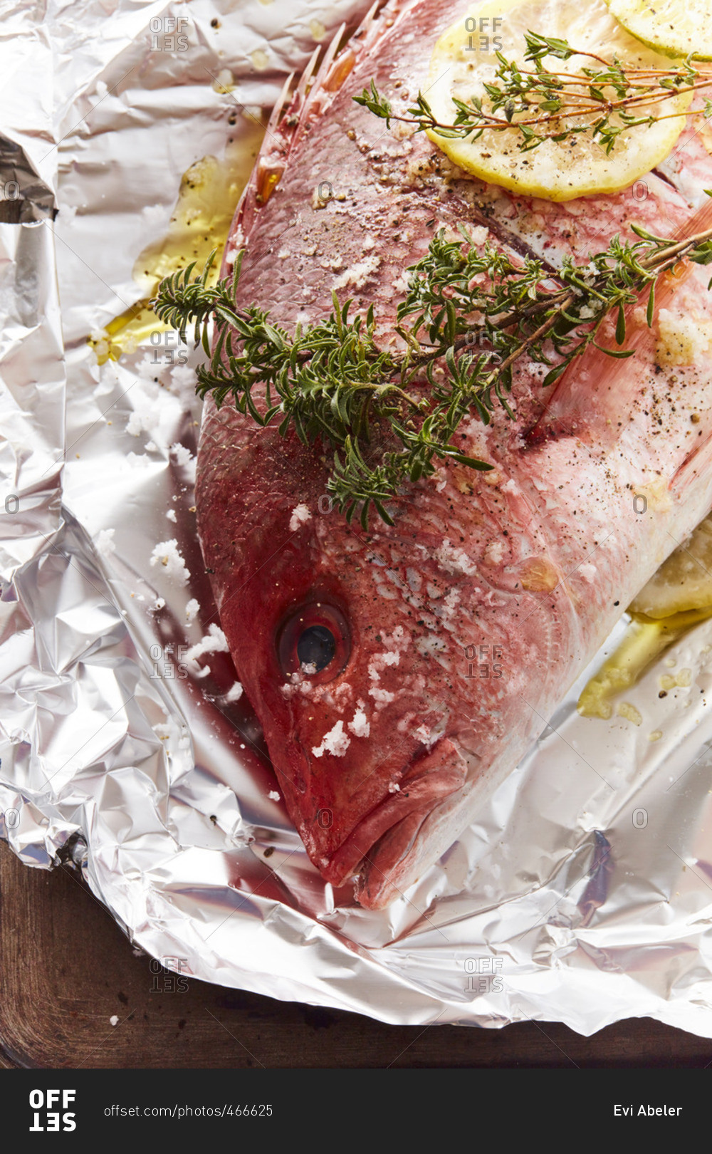 Red snapper on tin foil with herbs and lemon stock photo - OFFSET
